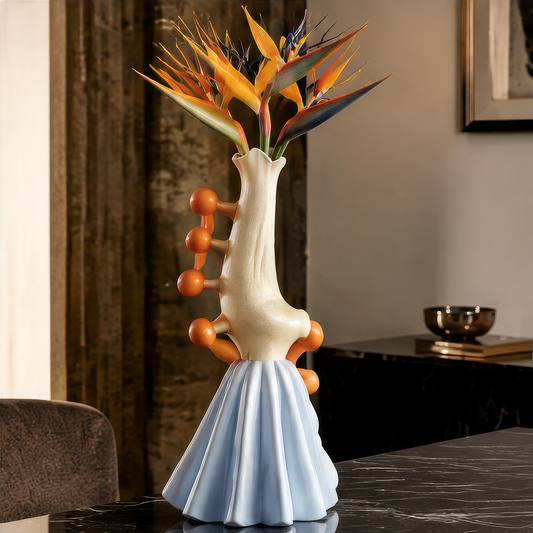 A Touch of Freshness — cream and sky blue sculptural vase with orange ball accents on dark marble with bird of paradise