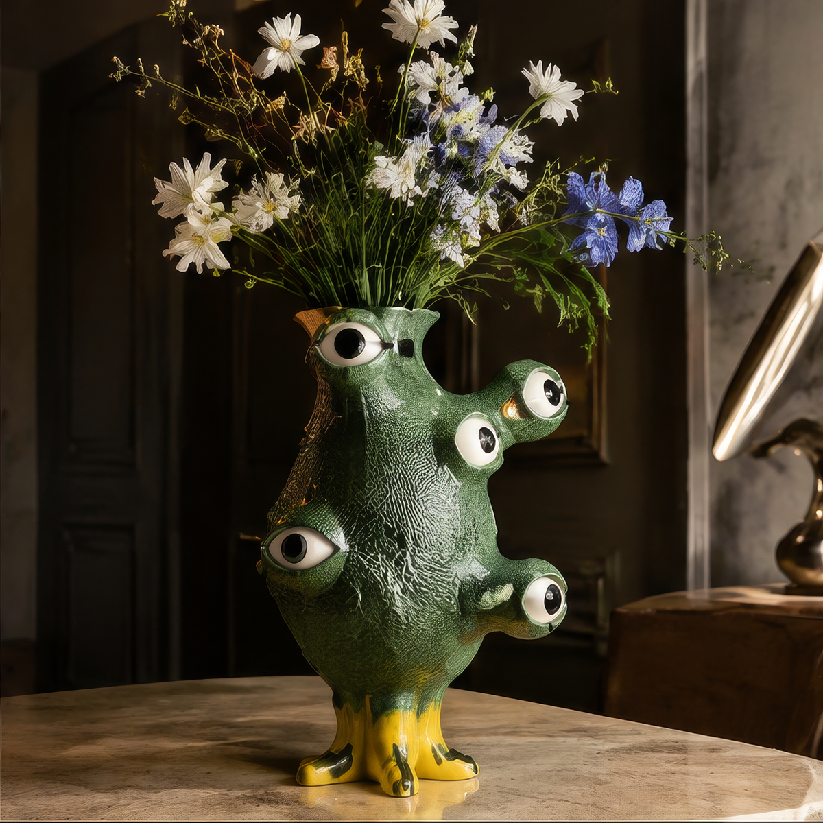Bring Artful Energy — overhead view of green monster vase with white daisies and blue flowers on warm stone surface